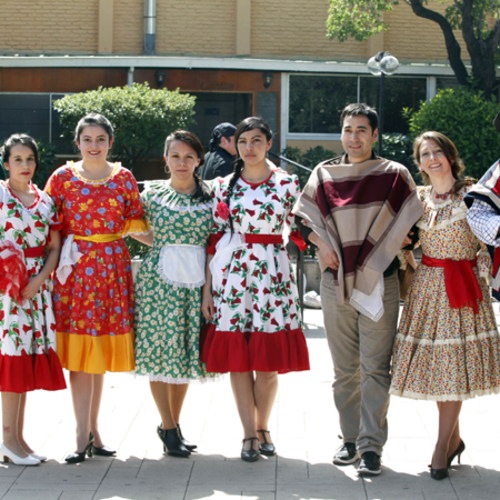 Group of people wearing traditional clothing stand in a line outdoors.